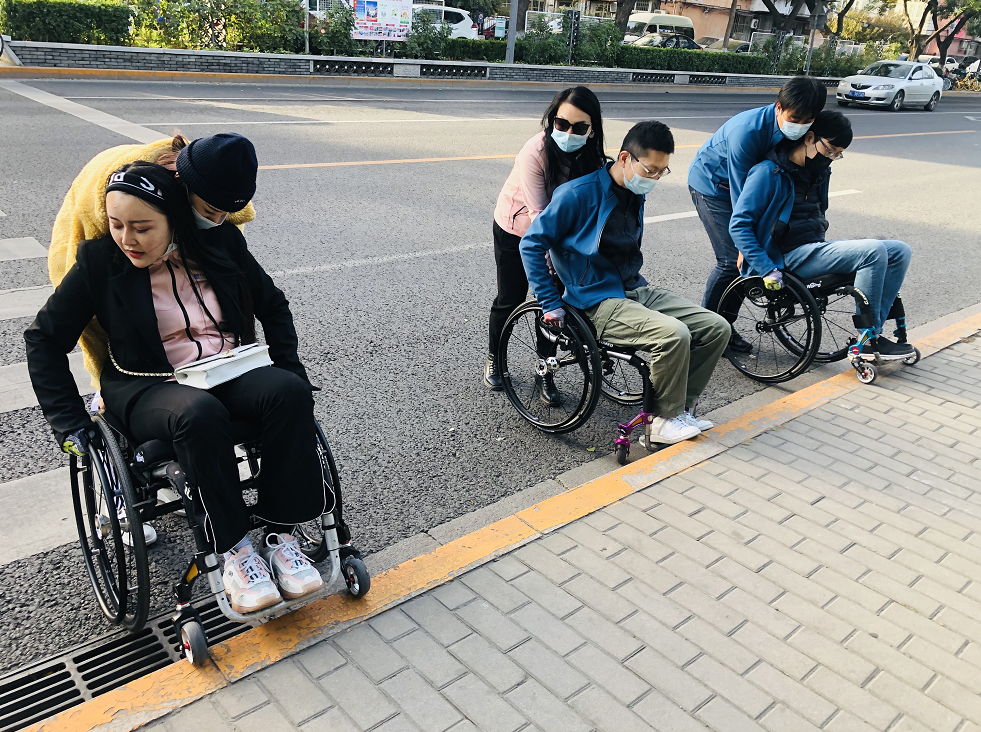 同学们在用轮椅体验高差较大的过街横道.png